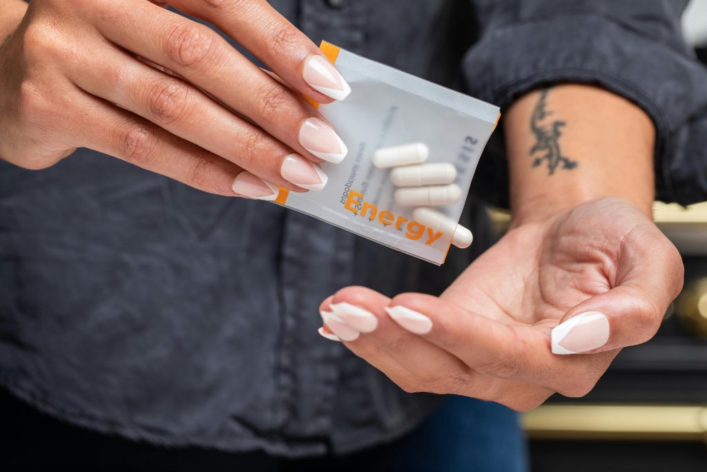 Close-up of woman's hands holding a packet of energy supplement capsules.