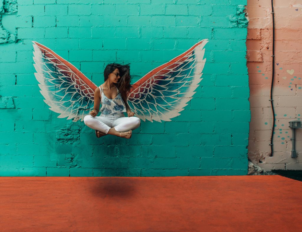 Woman posing in front of vibrant mural with angel wings in downtown Toronto.