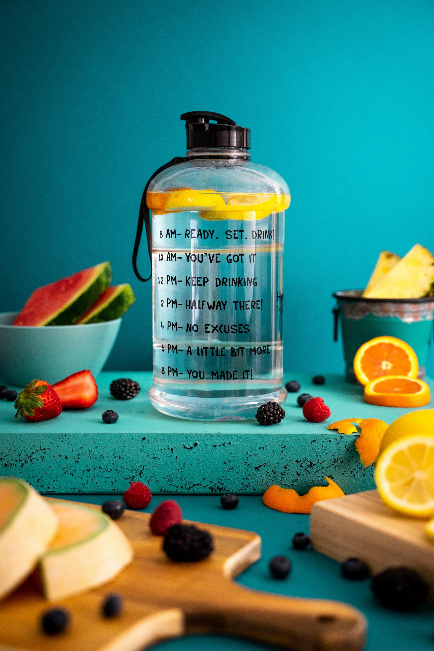 Bright composition of mixed fruits around a motivational water bottle indoors.